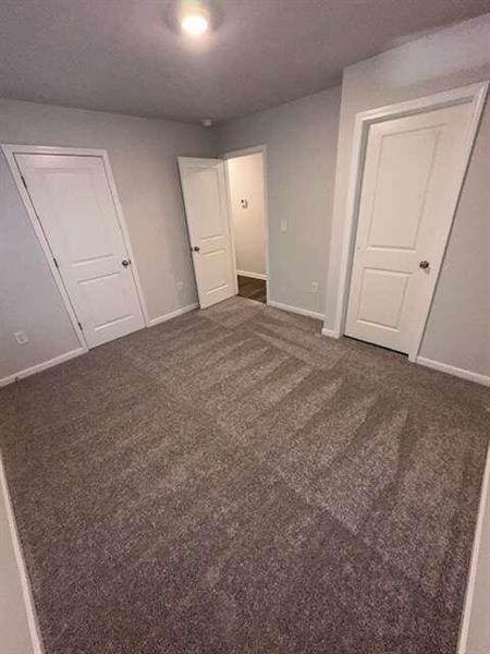 unfurnished bedroom with carpet, baseboards, and a textured ceiling