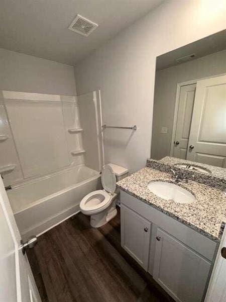 bathroom featuring vanity, wood finished floors, visible vents, shower / washtub combination, and toilet