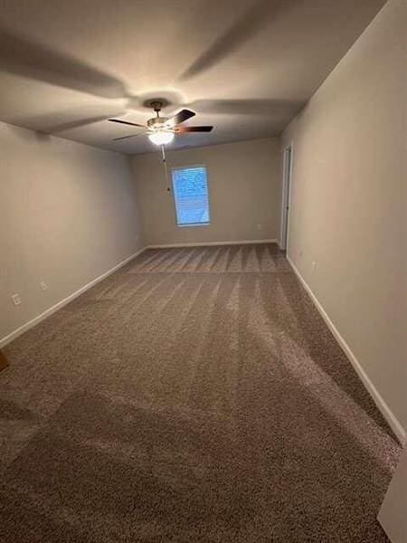 carpeted empty room with ceiling fan and baseboards