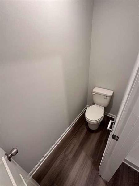 bathroom with toilet, wood finished floors, and baseboards