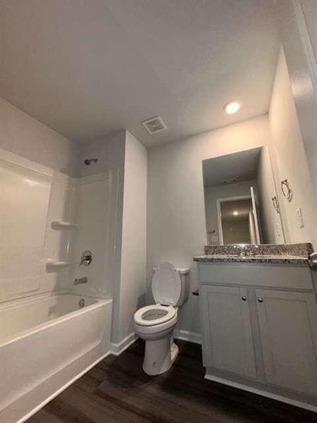 full bathroom featuring visible vents, toilet, wood finished floors, shower / bath combination, and vanity