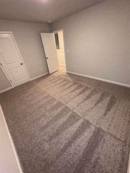 unfurnished room featuring carpet flooring and baseboards