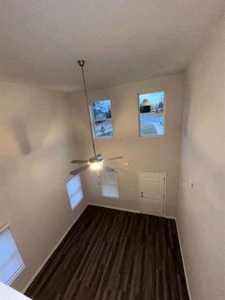 spare room featuring baseboards, a ceiling fan, and dark wood-style flooring