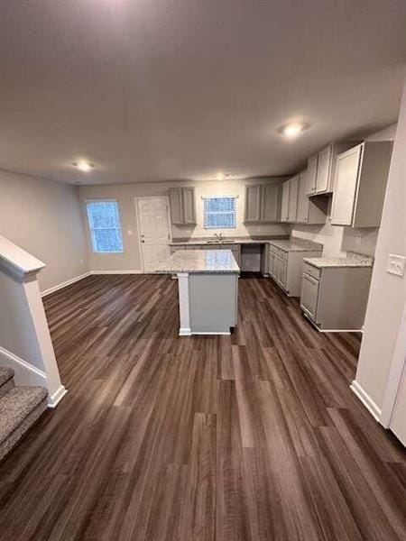 kitchen featuring baseboards, a kitchen island, dark wood finished floors, gray cabinets, and open floor plan