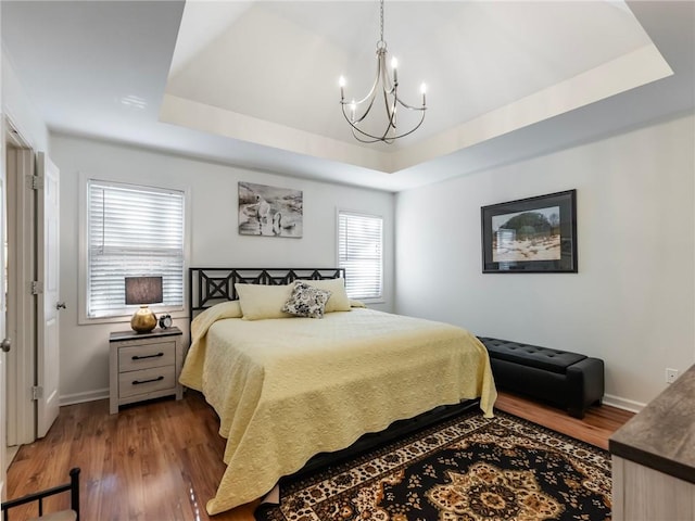 bedroom with a chandelier, dark hardwood / wood-style flooring, and a tray ceiling