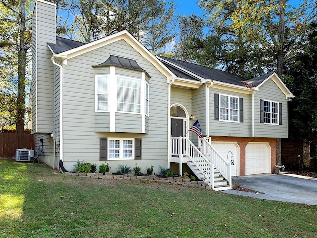 bi-level home with a front lawn, a garage, and cooling unit