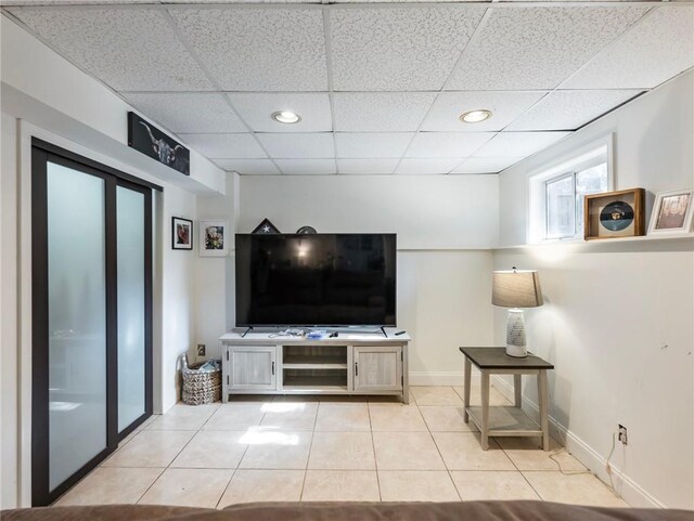 living room featuring a paneled ceiling and light tile patterned flooring