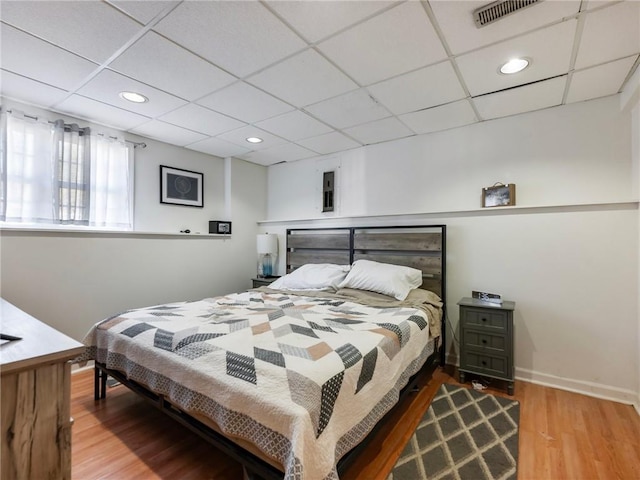 bedroom with hardwood / wood-style floors and a paneled ceiling