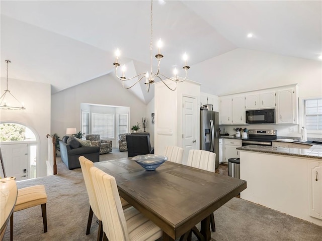 carpeted dining space featuring a healthy amount of sunlight, high vaulted ceiling, and an inviting chandelier