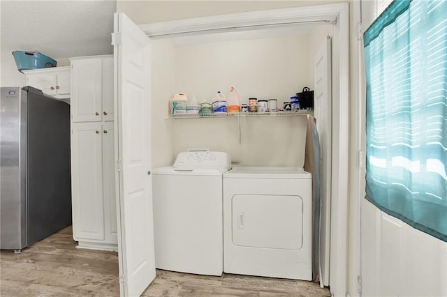 laundry area featuring washing machine and dryer and light wood-type flooring