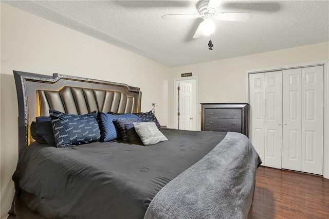 bedroom with a textured ceiling, dark wood-type flooring, a closet, and ceiling fan