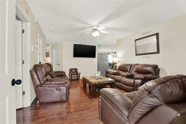 living room with ceiling fan, dark wood-type flooring, and a textured ceiling