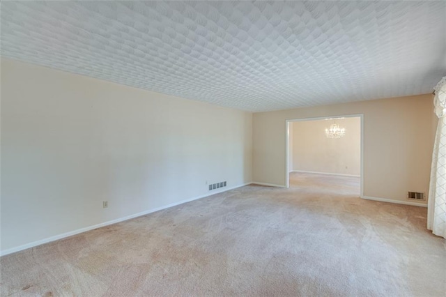 empty room featuring an inviting chandelier and light colored carpet