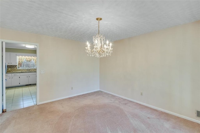 carpeted spare room featuring a notable chandelier