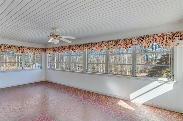 unfurnished sunroom featuring ceiling fan, a wealth of natural light, and wood ceiling