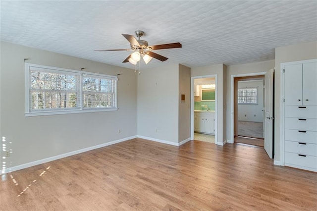 unfurnished room with light hardwood / wood-style floors, a textured ceiling, and a wealth of natural light