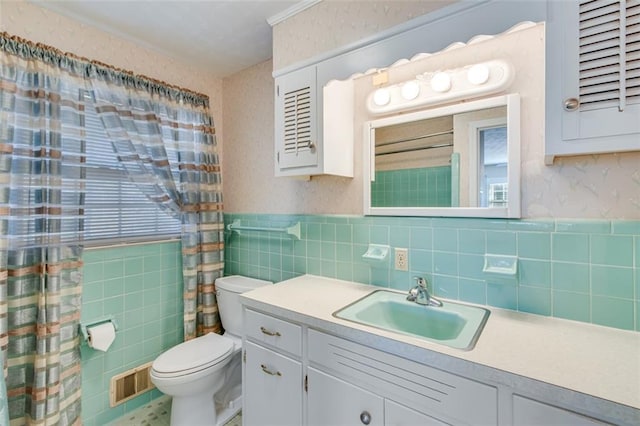 bathroom featuring vanity, toilet, and tile walls