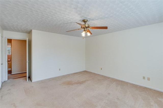 unfurnished room with ceiling fan, light colored carpet, and a textured ceiling