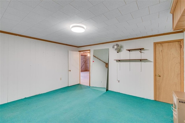 carpeted empty room with crown molding and wooden walls