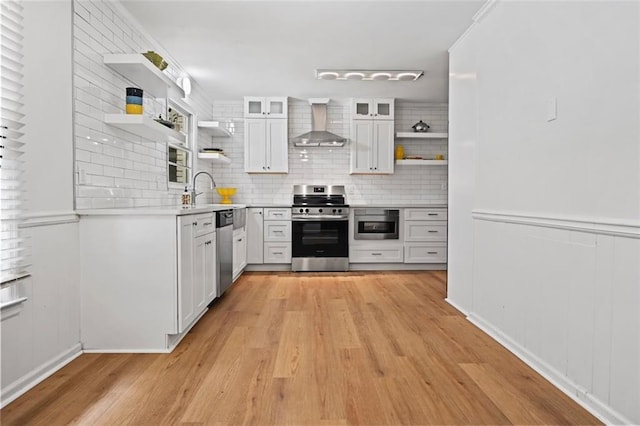3332 Saint John Dr, East Point, GA 30344 - kitchen with open shelves, stainless steel appliances, wall chimney exhaust hood, light wood finished floors, and white cabinetry