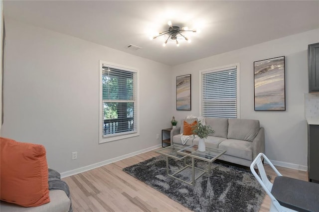 living room with light wood-style floors, baseboards, and visible vents