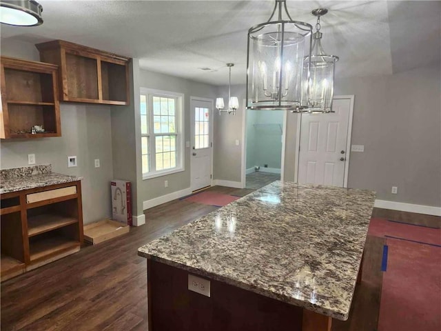 kitchen with dark hardwood / wood-style flooring, light stone countertops, hanging light fixtures, and a notable chandelier