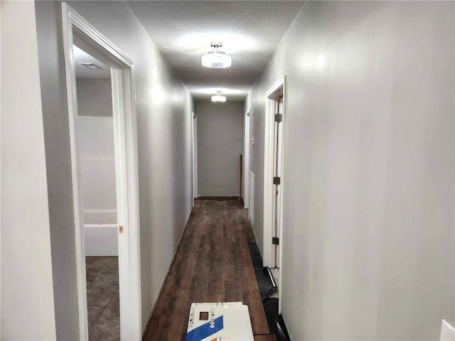 corridor with dark wood-type flooring and a textured ceiling