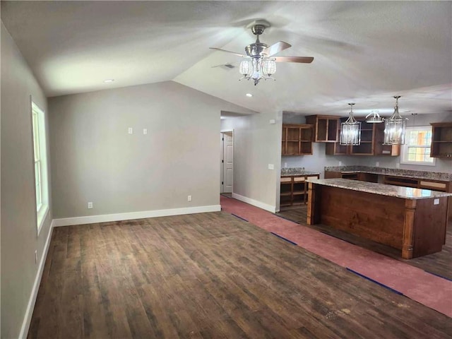 kitchen featuring lofted ceiling, hanging light fixtures, a center island, ceiling fan, and dark wood-type flooring