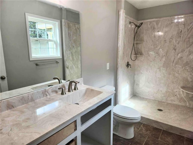 bathroom featuring vanity, a tile shower, and toilet