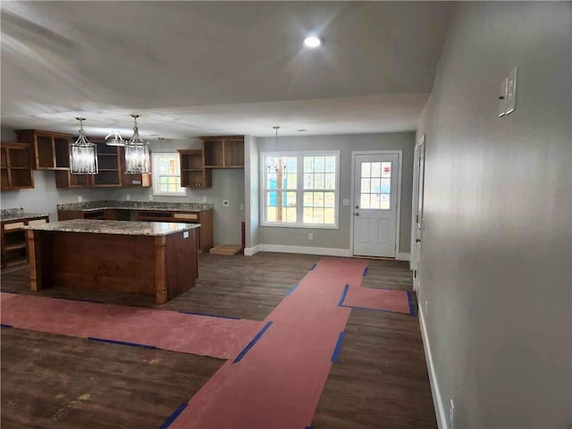 kitchen featuring dark wood-type flooring, a healthy amount of sunlight, a kitchen island, decorative light fixtures, and a chandelier