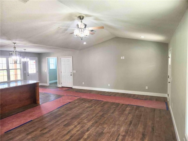 interior space featuring ceiling fan with notable chandelier, dark hardwood / wood-style flooring, and vaulted ceiling