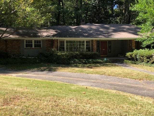 ranch-style house featuring brick siding, a front lawn, and driveway