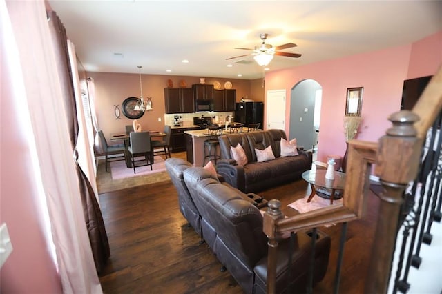 living room with dark wood-style floors, arched walkways, a ceiling fan, and recessed lighting