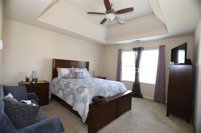 bedroom featuring a tray ceiling, light colored carpet, and ceiling fan