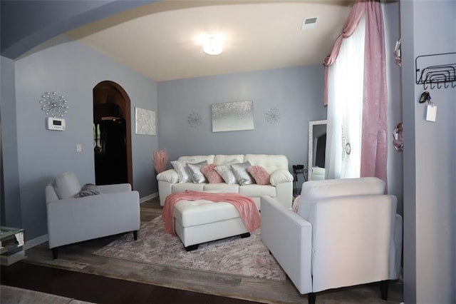 living area with visible vents, baseboards, arched walkways, and wood finished floors