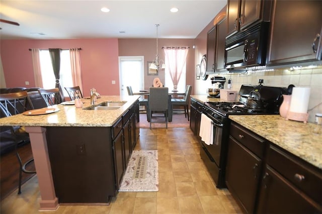 kitchen featuring a sink, black appliances, a kitchen breakfast bar, and plenty of natural light