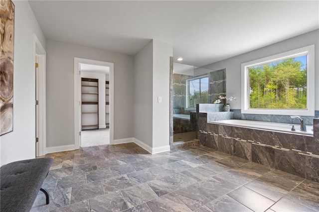 full bath featuring recessed lighting, a shower stall, stone finish flooring, baseboards, and a garden tub