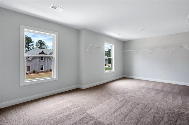carpeted empty room featuring baseboards and visible vents