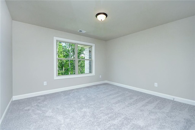 carpeted spare room with visible vents and baseboards