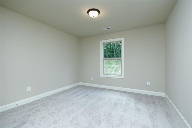 carpeted spare room with visible vents and baseboards