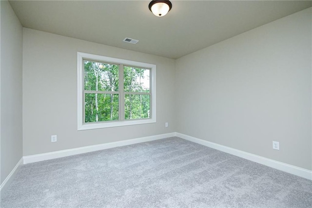carpeted spare room with visible vents and baseboards