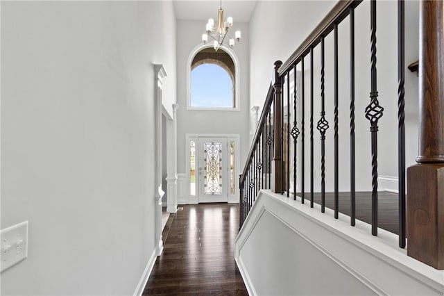 entryway featuring a notable chandelier, dark wood-type flooring, and a high ceiling