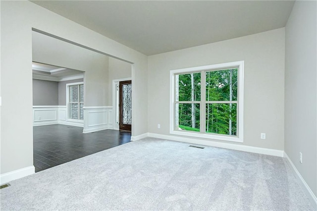 carpeted spare room with visible vents, a wainscoted wall, and baseboards