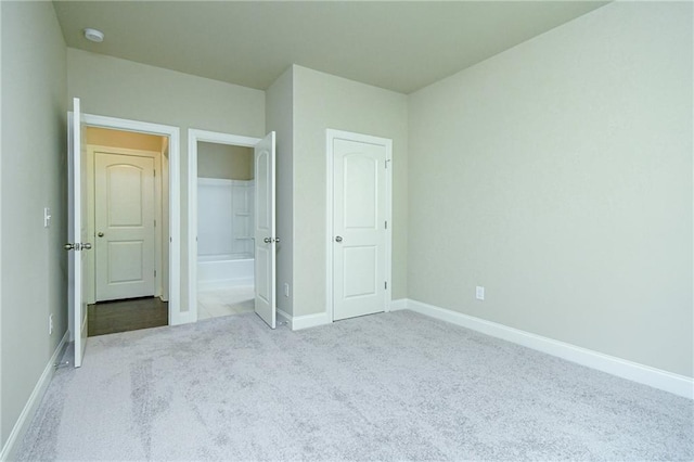 unfurnished bedroom with baseboards, ensuite bath, and carpet floors
