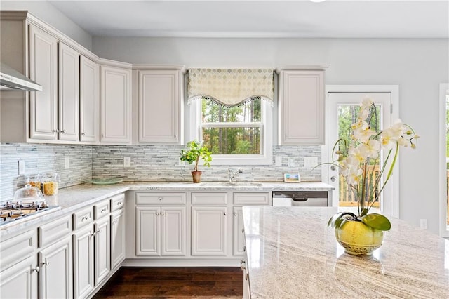 kitchen featuring stainless steel dishwasher, light stone countertops, tasteful backsplash, and a healthy amount of sunlight