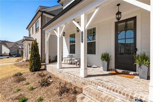 doorway to property with a porch and brick siding