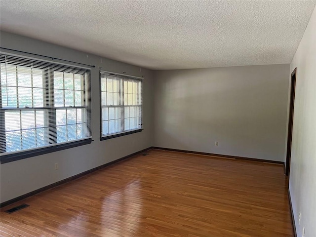 unfurnished room featuring hardwood / wood-style floors and a textured ceiling