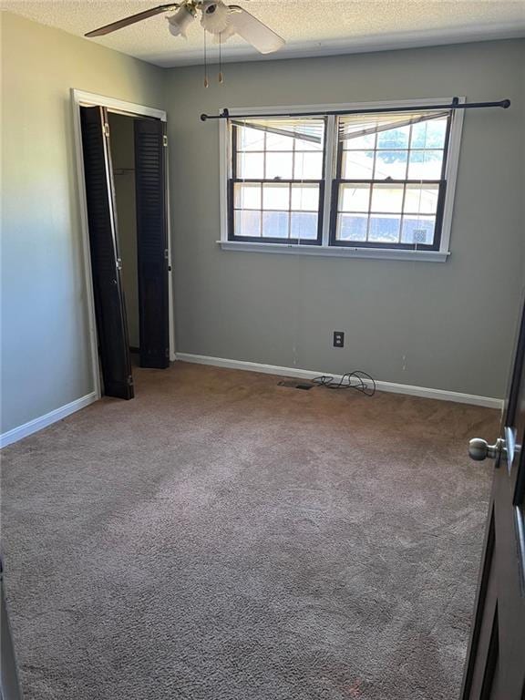 carpeted spare room featuring ceiling fan and a textured ceiling