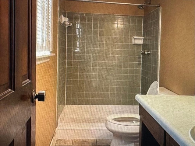 bathroom featuring vanity, tiled shower, toilet, and tile patterned flooring