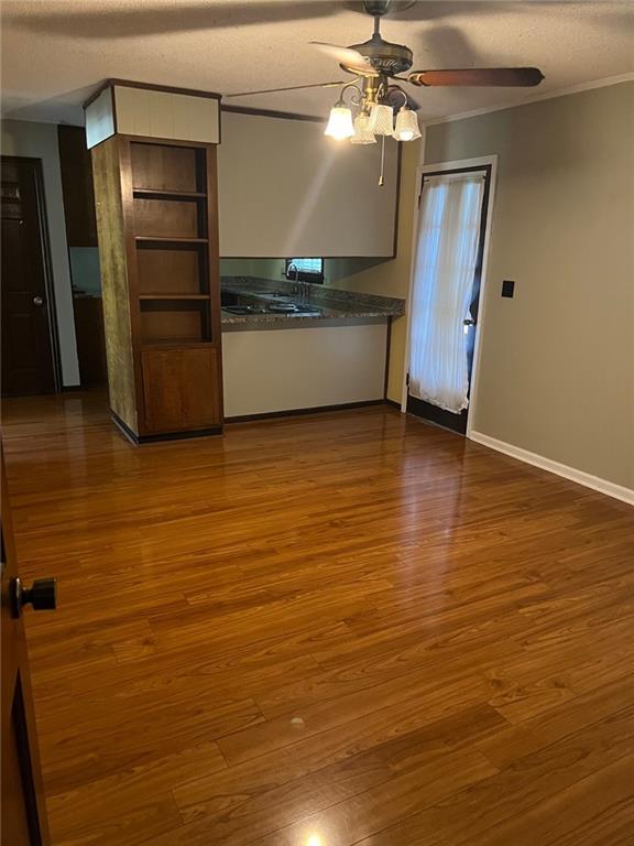 kitchen with ornamental molding, ceiling fan, a textured ceiling, and dark hardwood / wood-style flooring